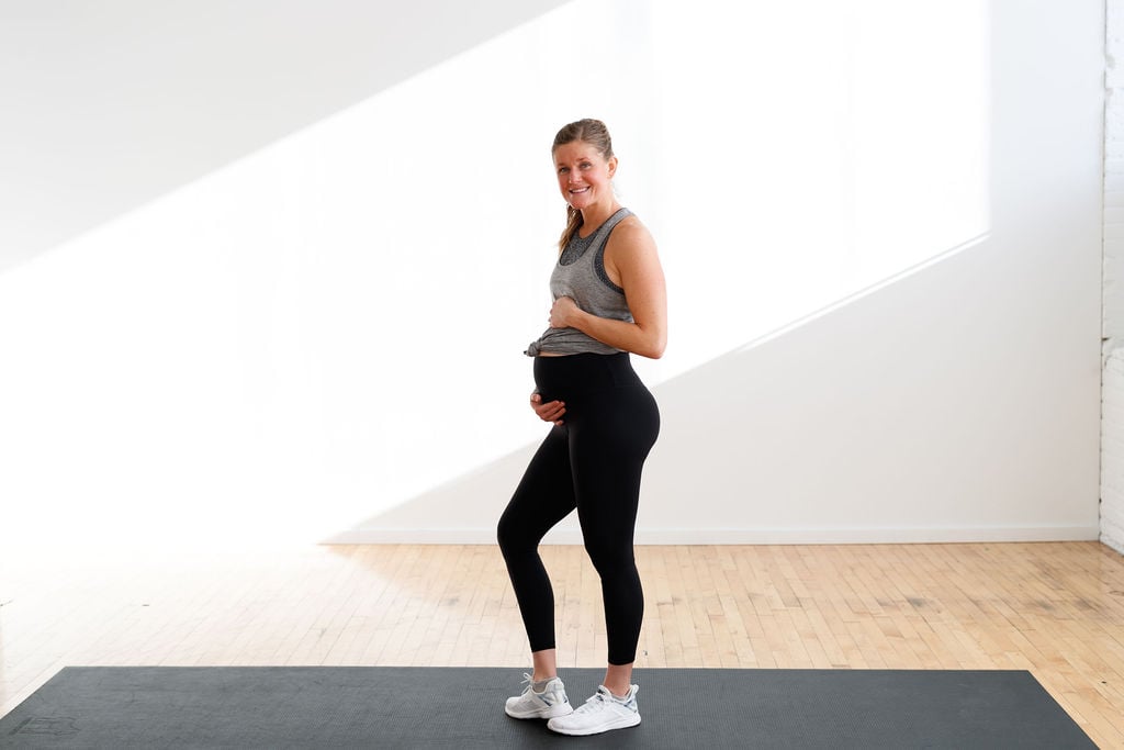 Pregnant women in workout gear holding her belly. 