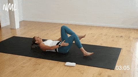 woman performing a lying pretzel stretch as part of a hip flexor stretch routine