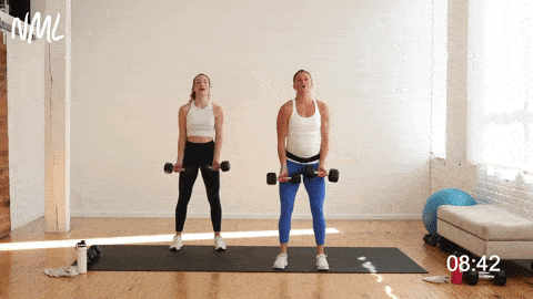 two women performing a standing chest fly with dumbbells in an arm workout