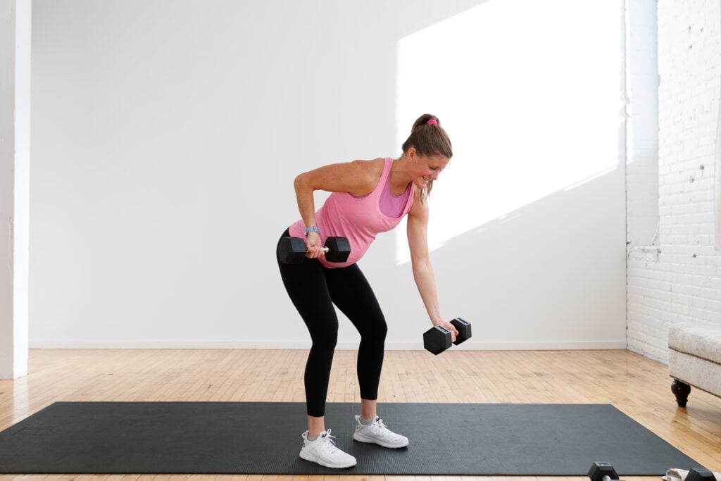 pregnant woman performing an alternating back row with dumbbells in a prenatal arm workout