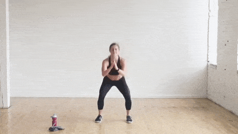 woman performing air squat and calf raise as part of HIIT Cardio workout