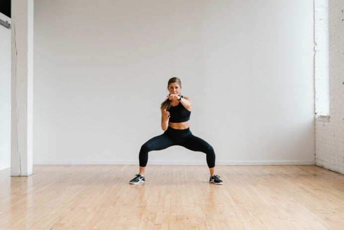 Sumo squat hold and cross body punch during a HIIT Cardio Workout.