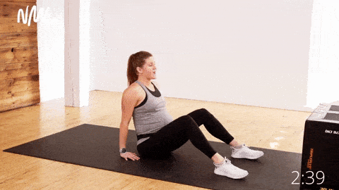 Pregnant woman performing seated heel slides on the mat. Pregnancy Ab Workout
