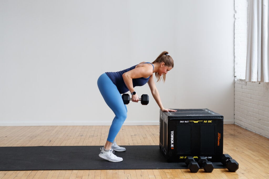 Pregnant woman performing a bent over row on bench with a dumbbell. 