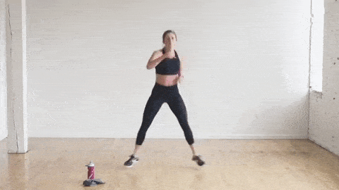 woman performing sumo squat jack and with punches, bodyweight HIIT cardio workout