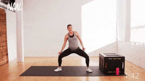 Pregnant woman performing oblique reaches from a loaded sumo squat stance.