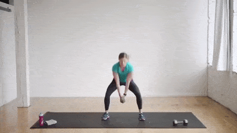 woman performing a dumbbell wood chop swing and jack as part of a full body HIIT workout