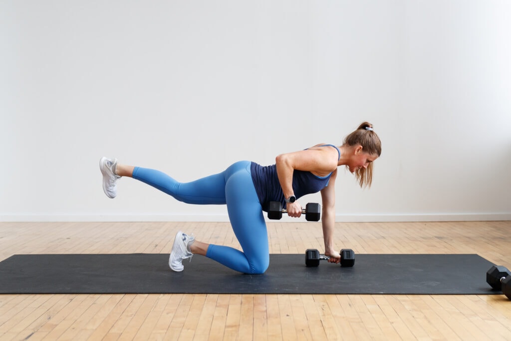 pregnant woman performing a bird dog single arm back row with dummbells