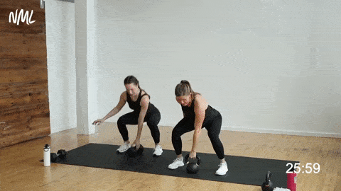 How to do kettlebell pick up squats; two women squatting to pick up a kettlebell from the ground.