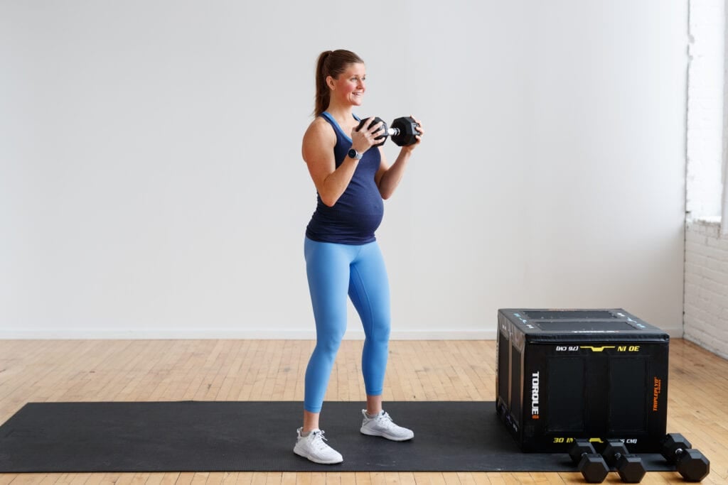 pregnant woman performing bicep curl with one dumbbell