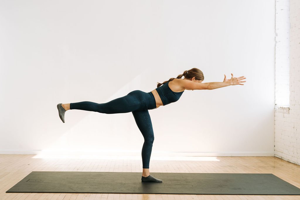 A bodyweight intense yoga workout with no equipment. Woman performing Warrior Three yoga pose.