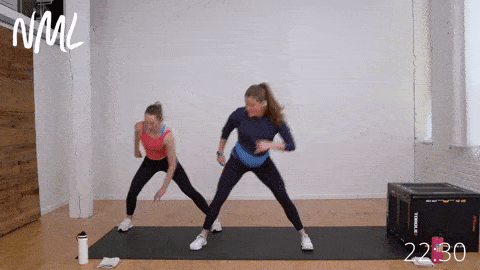 two women performing three lateral squats followed by a lateral shuffle as part of cardio and mobility workout