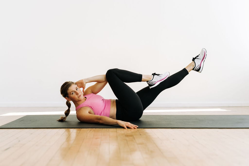 woman laying on her back performing a single sided crunch