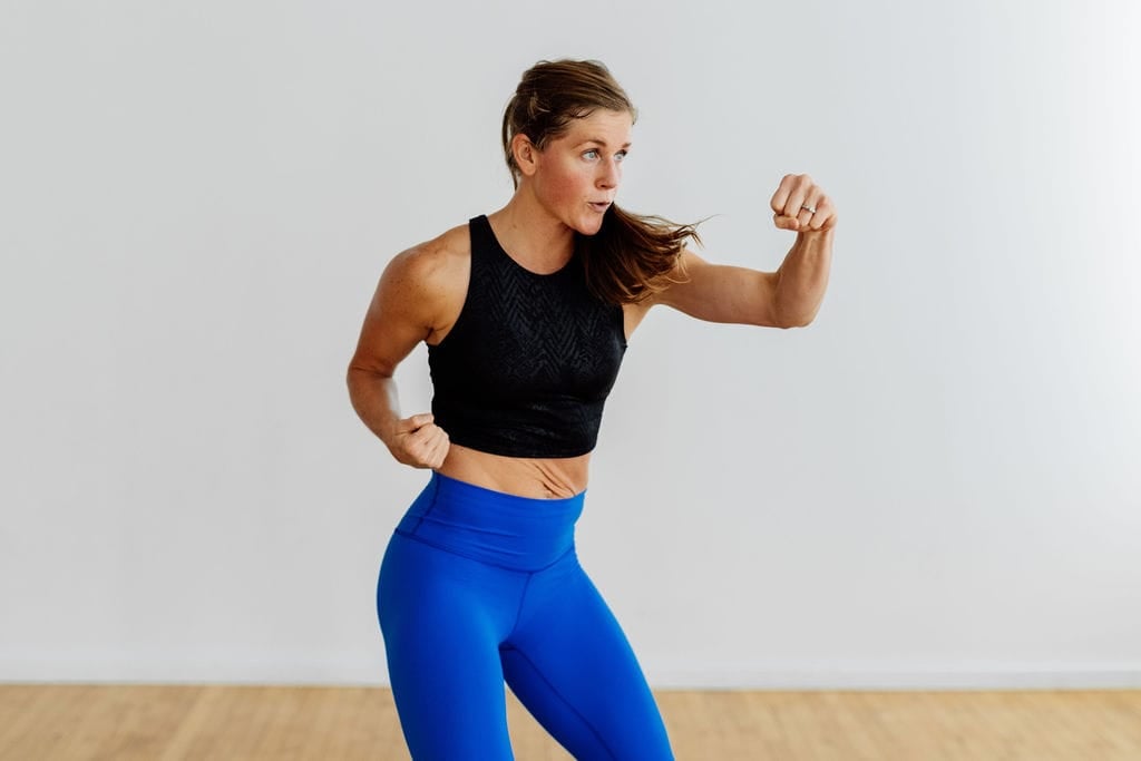 Woman performing a punch in this full body bodyweight HIIT workout at home.