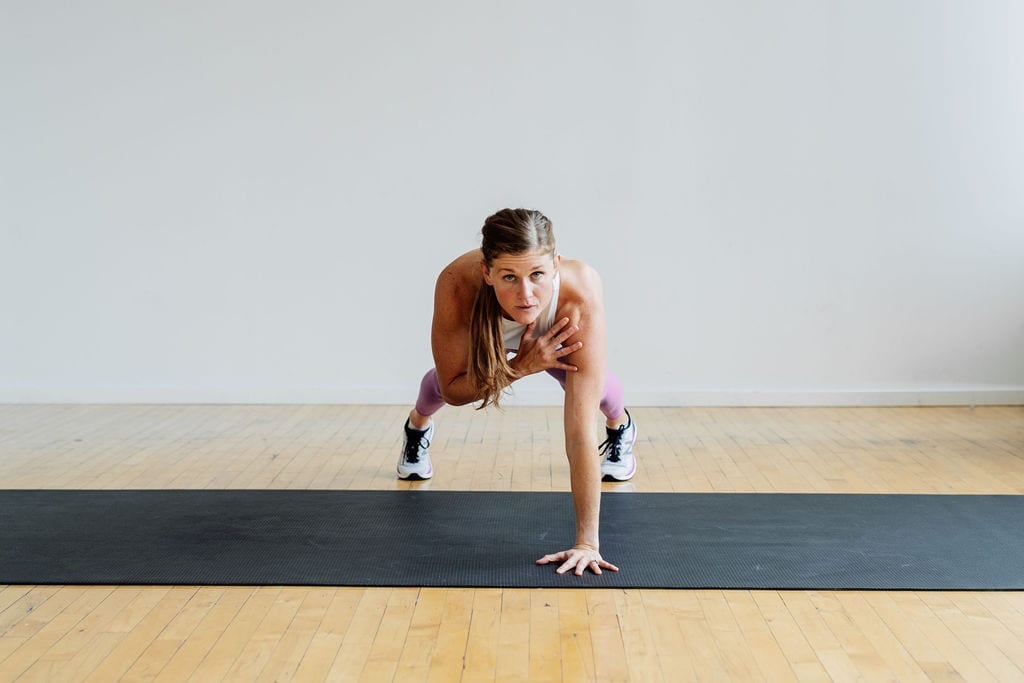 Woman performing a push up and shoulder tap in this no equipment arm workout.