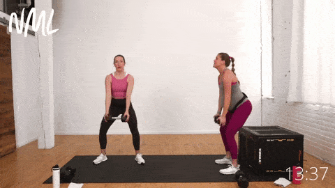 two women, one pregnant, performing a squat and dumbbell front raise