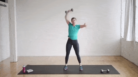 woman performing a burpee and alternating single arm dumbbell snatch in a full body HIIT workout at home