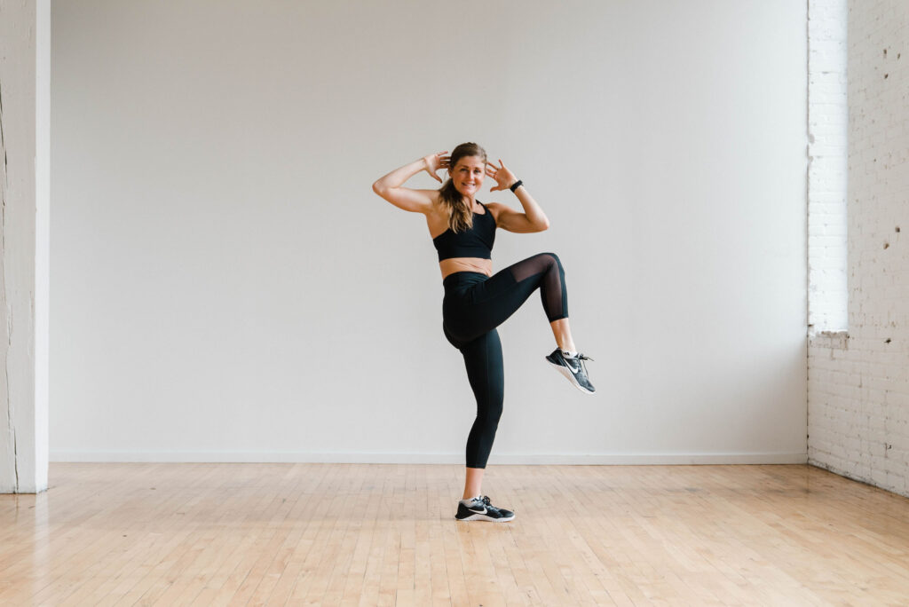 A women performing a reverse crossbody crunch with a reverse lunge during a HIIT Cardio Workout. 