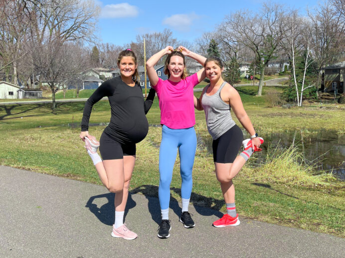 3 women wearing running gear standing on a trail