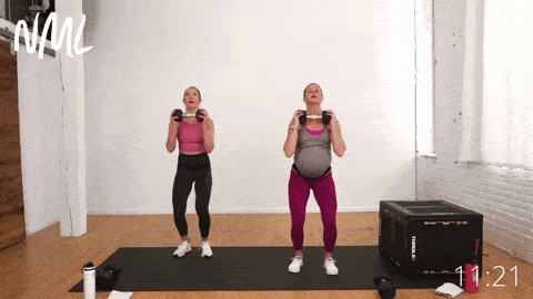 two women, one pregnant, performing a dumbbell overhead press and jack