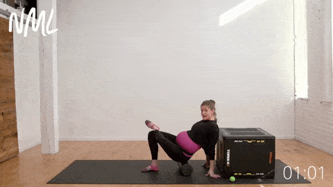 woman performing a seated piriformis release on a foam roller to relieve sciatica pain