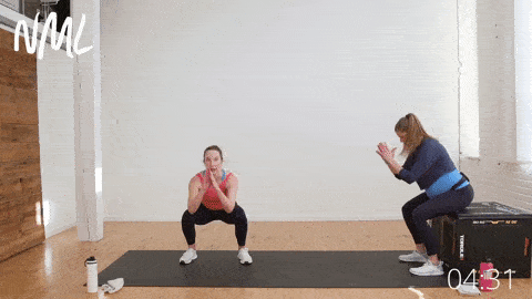 a pregnant woman performing a bodyweight box squat as part of prenatal cardio workout