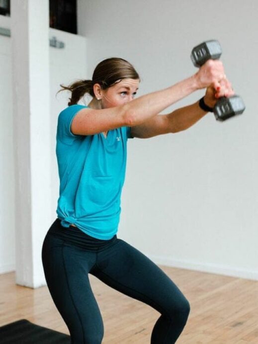 Woman performing wood-chop exercise with one dumbbell with text overlay full body HIIT workout for women