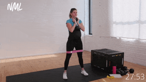 pregnant woman performing goblet squats with a mini loop resistance band around her legs