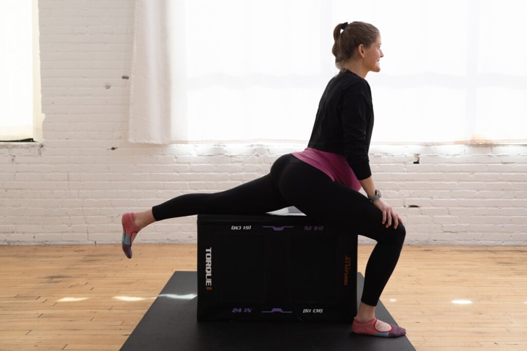 woman performing a supported hip flexor stretch to relieve sciatica pain