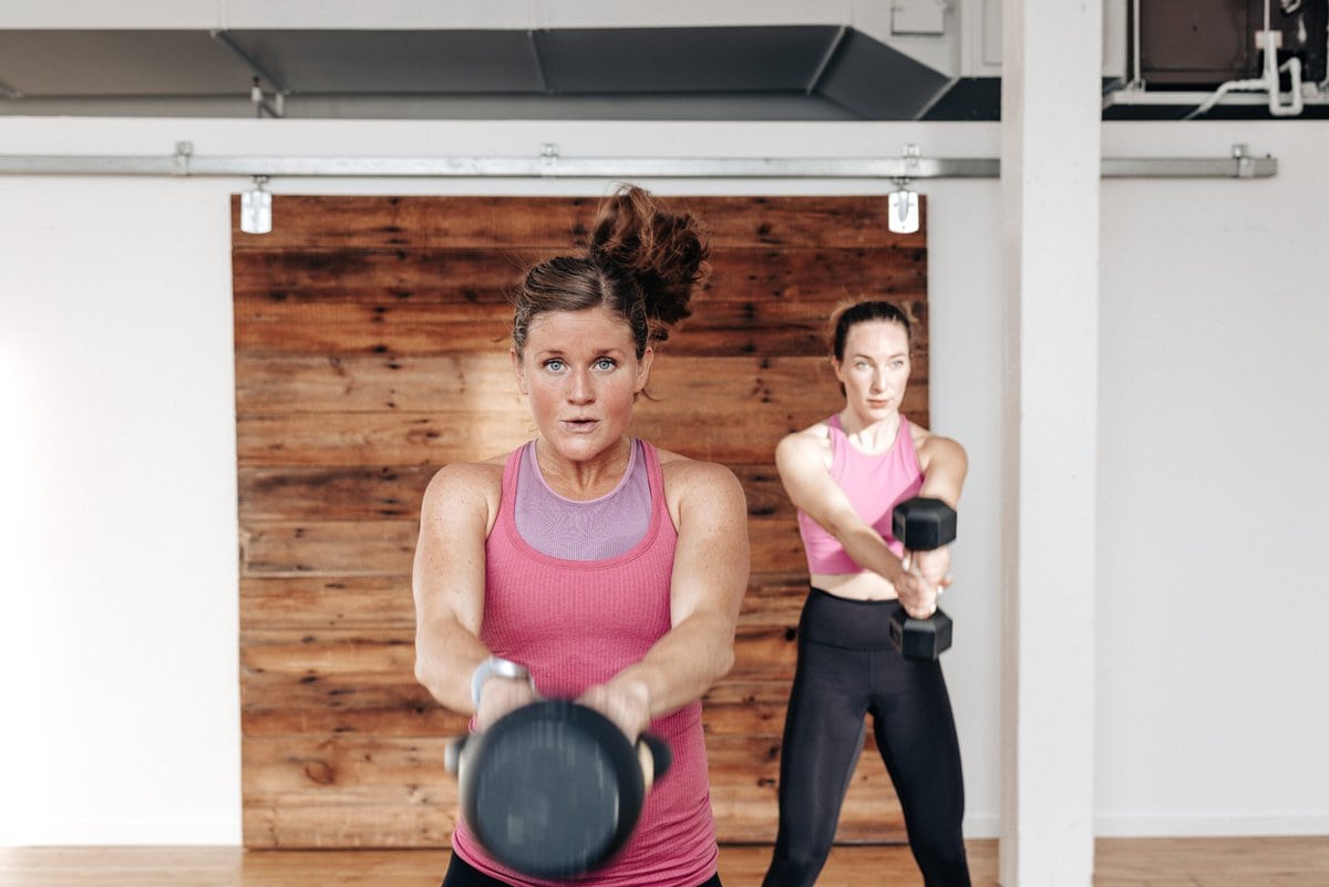 two women performing a kettlebell swing