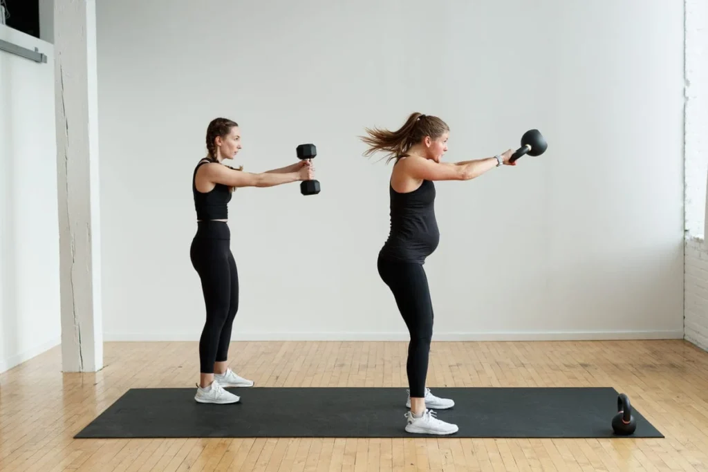 two women performing kettlebell swings in a leg workout at home