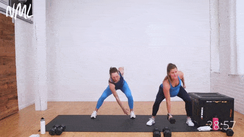two women performing a lateral dumbbell shuffle