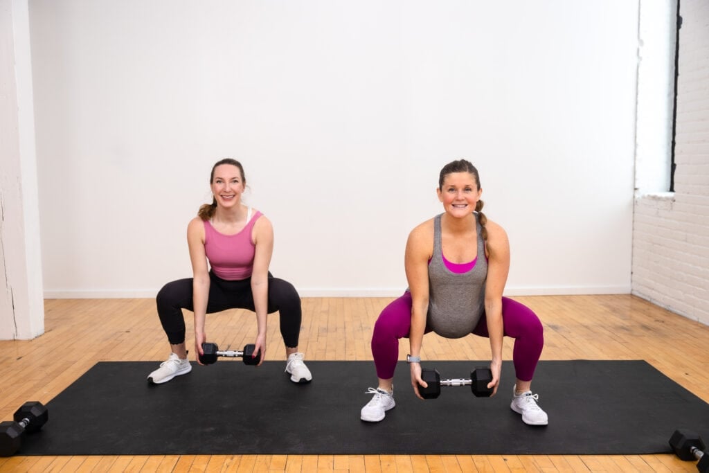 two women, one pregnant, performing a dumbbell squat