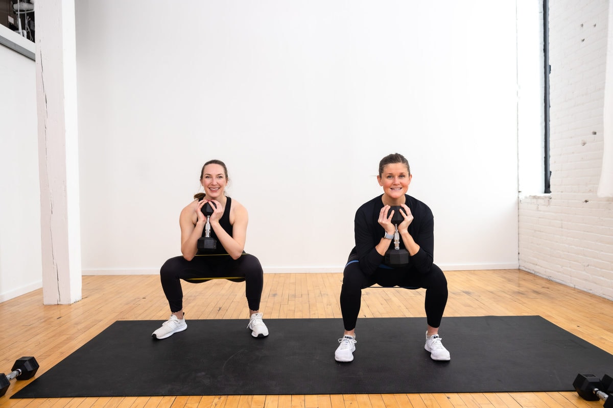 two women (one pregnant woman) performing a weighted goblet squuat as part of a pregnancy leg workout