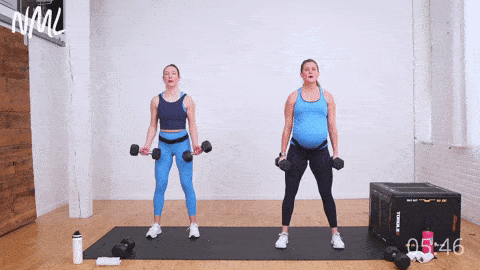 two women, one pregnant woman performing two bicep curls and two squats. Part of an advanced pregnancy workout at home. 