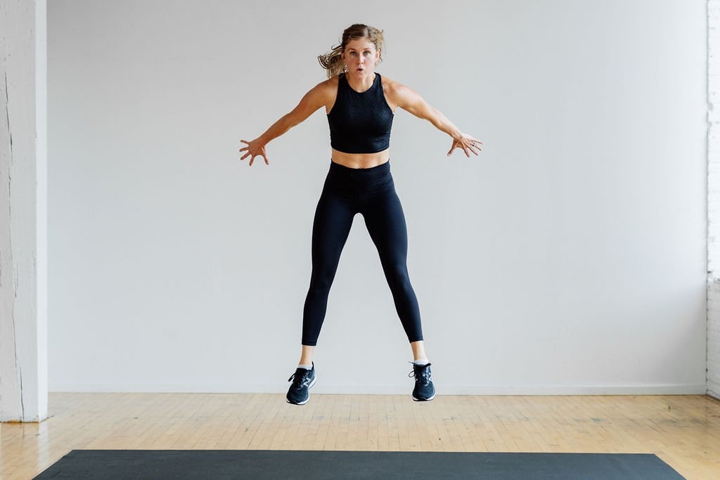 woman performing a squat jump in the best strength and hiit workout for women at home