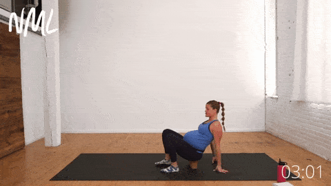 pregnant woman performing a supported seated figure 4 pose on a yoga block in prenatal yoga routine