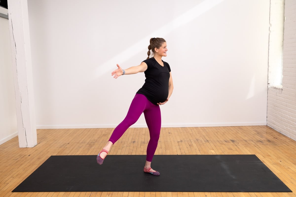pregnant woman performing a standing side leg lift as part of pregnancy barre workout