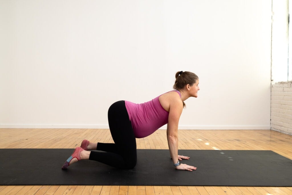 pregnant woman performing cow pose as part of prenatal pilates workout