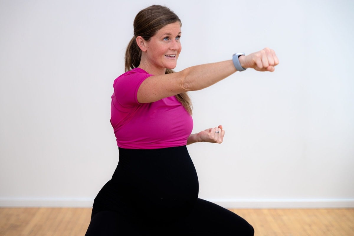 pregnant woman in her third trimester of of pregnancy performing a crossbody punch. 
