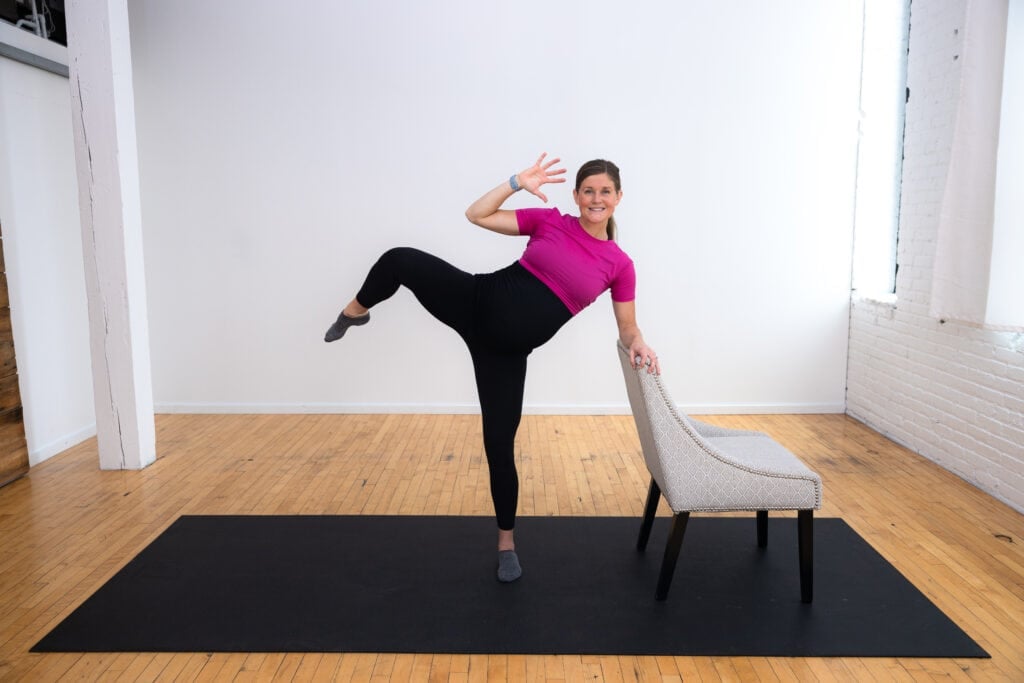 pregnant woman performing a supported oblique crunch as part of a pregnancy barre workout 