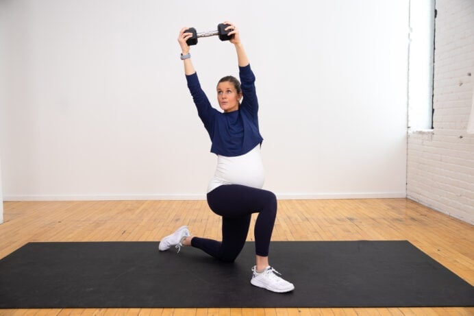 pregnant woman in a kneeling position performing a core exercise with one dumbbell