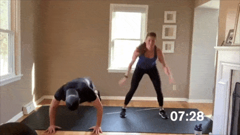 man and woman performing burpees in a HIIT workout at home