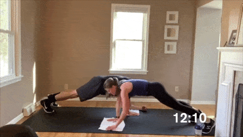 man and woman performing a plank and army crawl in a cardio workout at home