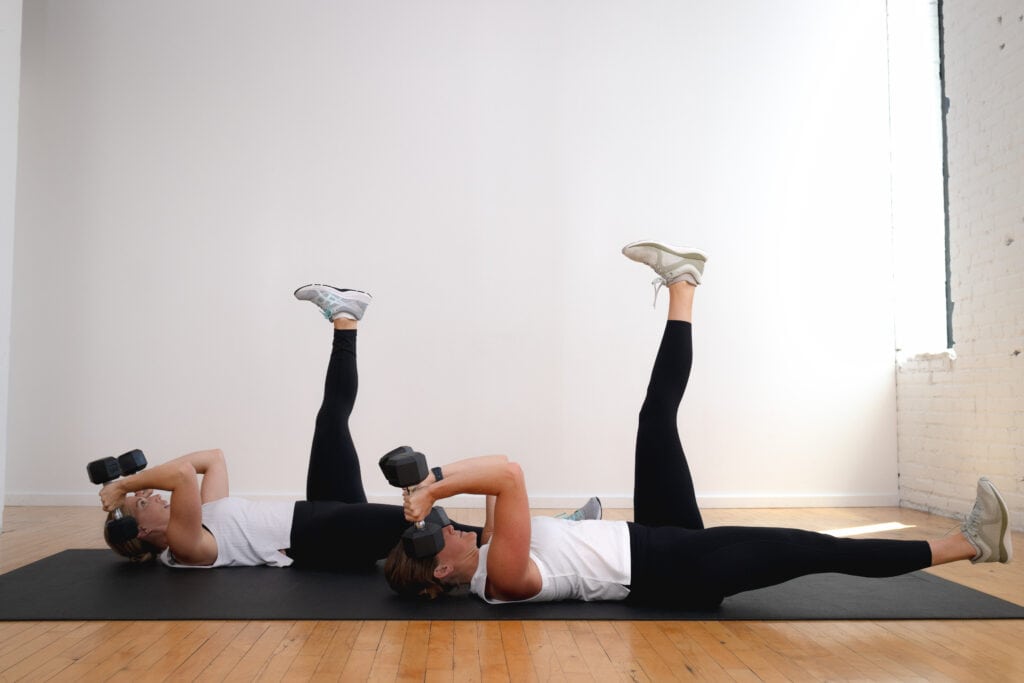 two women lying on their backs performing skull crushers