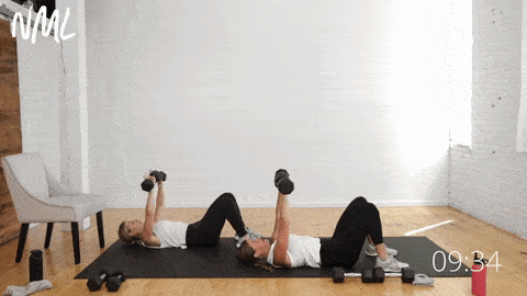 two women lying on their backs performing a standard dumbbell chest press