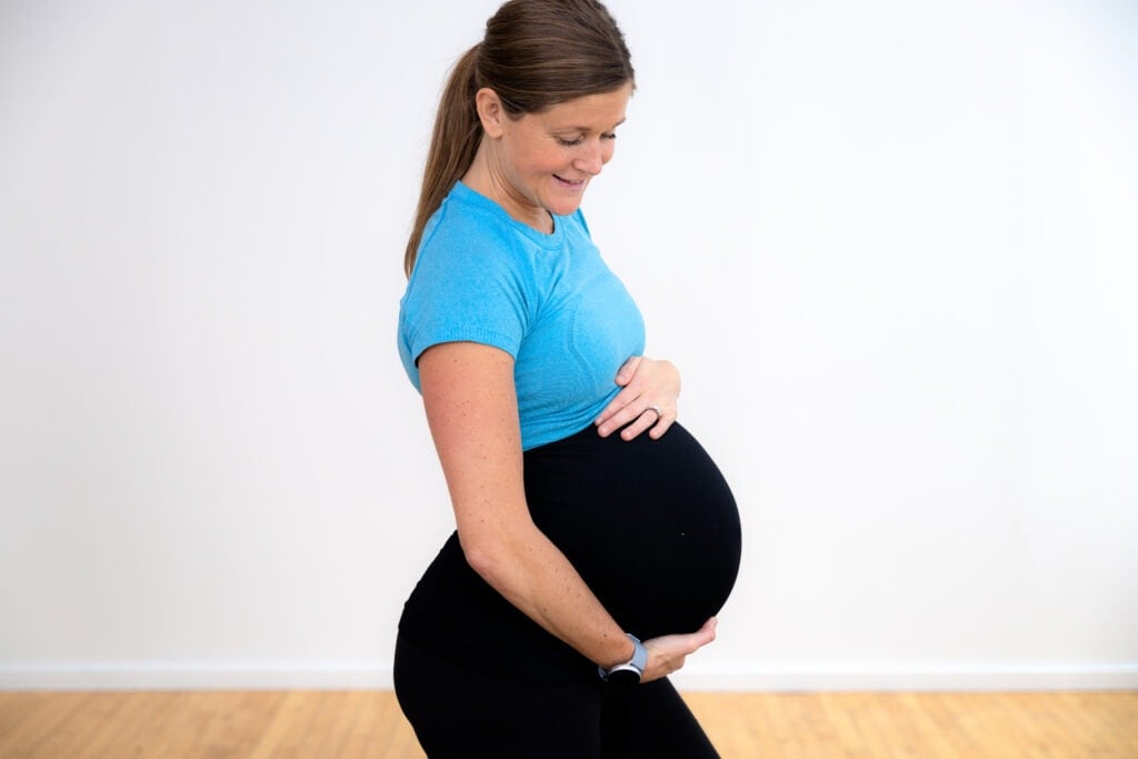 pregnant woman holding her baby bump as part of third trimester pregnancy workout plan