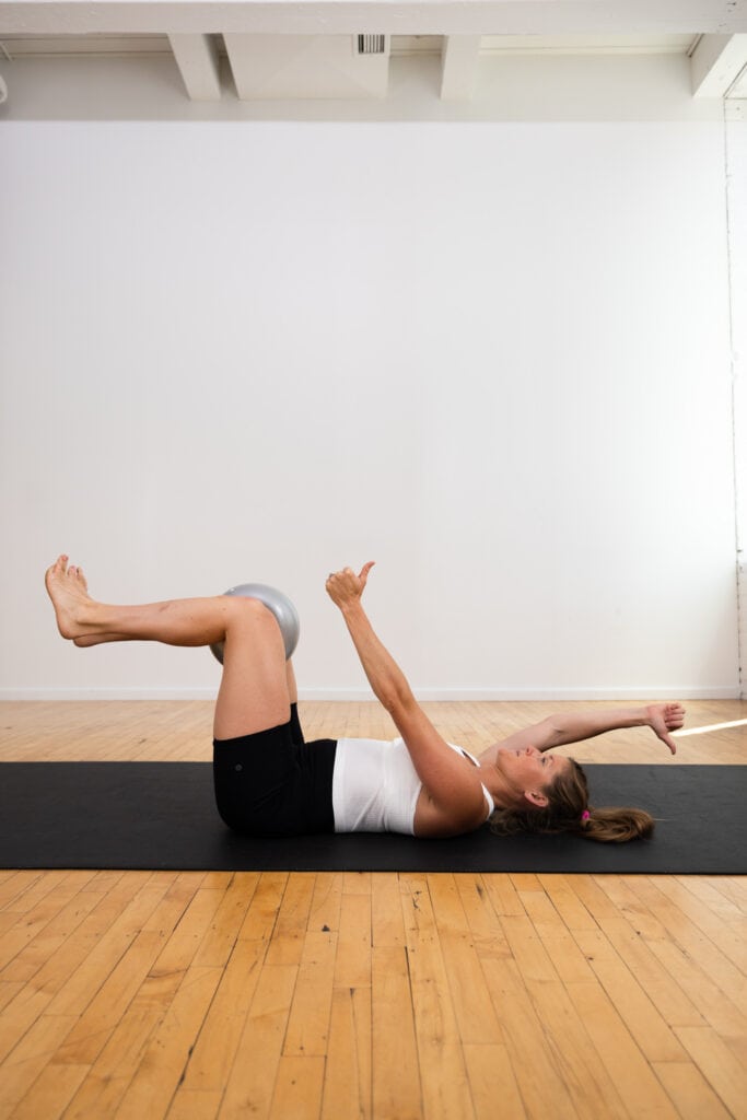 postpartum woman lying on her back performing a deadbug exercise