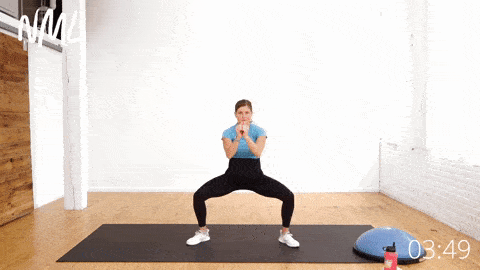 pregnant woman performing a wide squat and pulsing motion