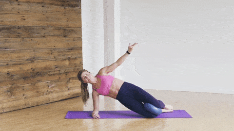 woman performing a modified side plank and hip lift with pilates ball between knees to engage core